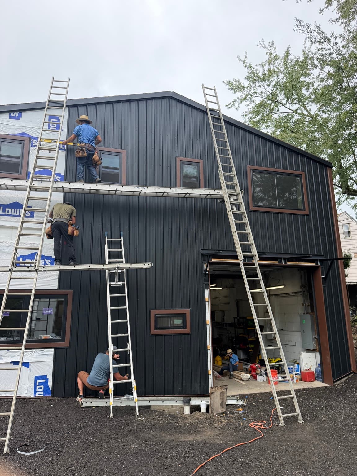 Crew installing vertical black metal siding