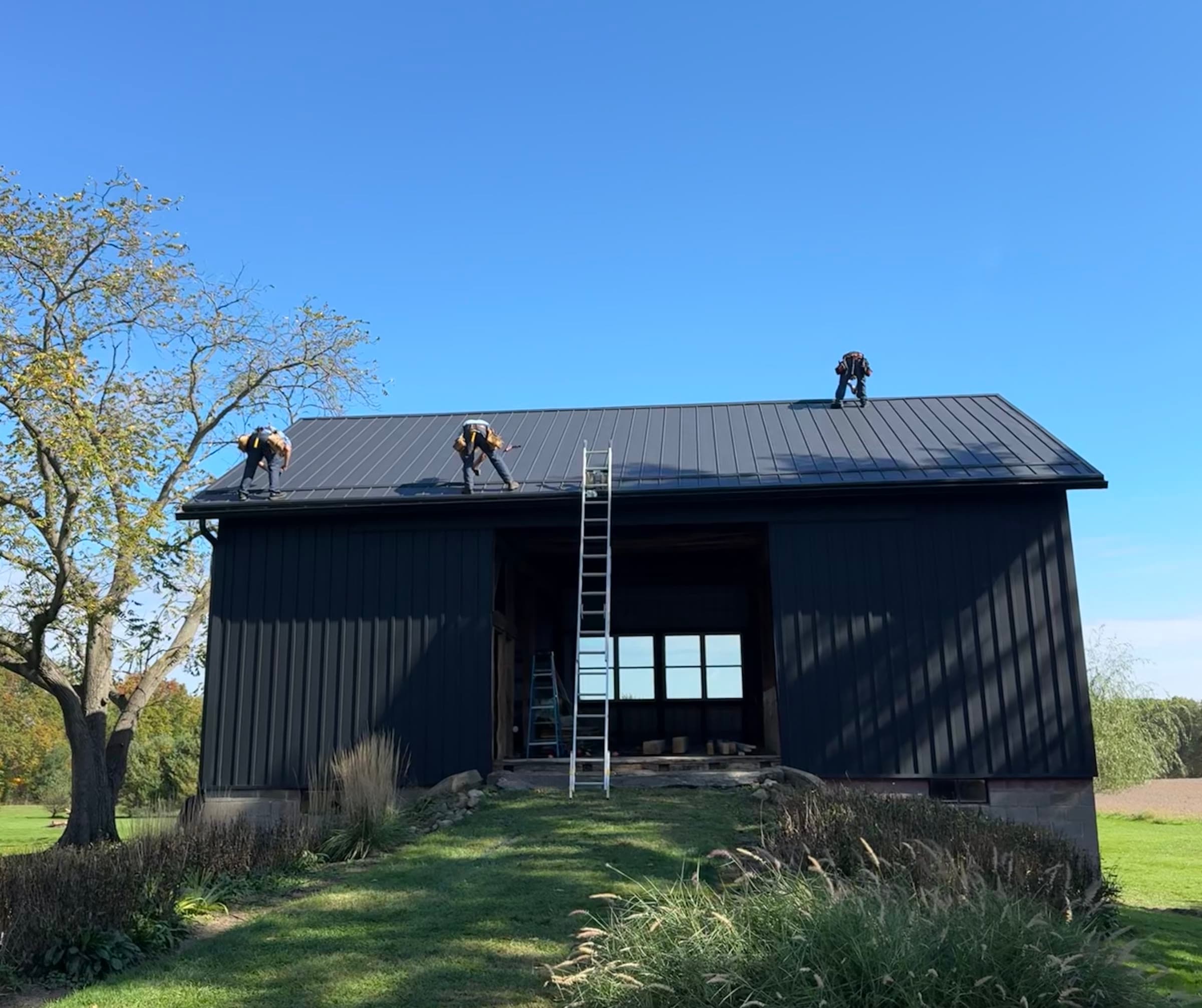 Barn front with black metal siding and standing-seam roof after renovation