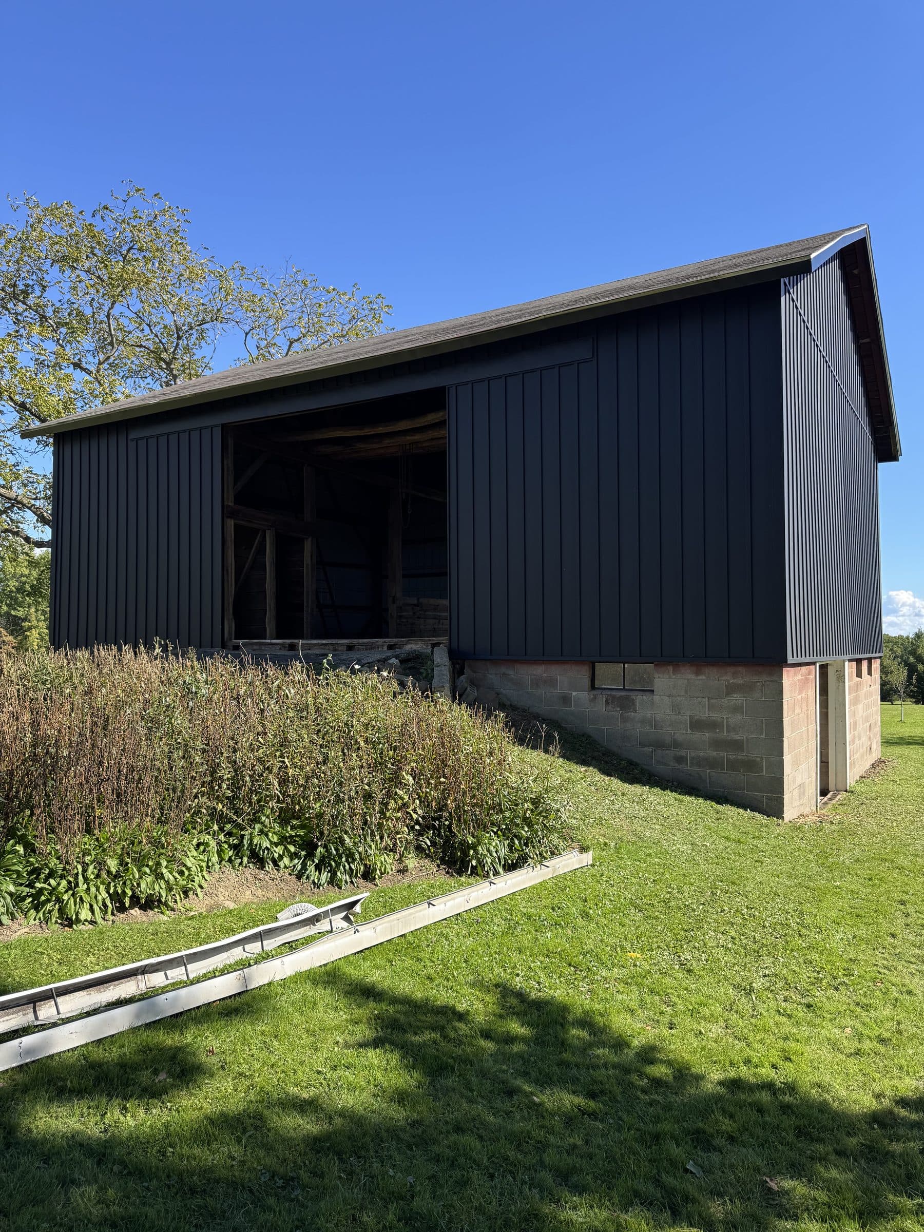 Completed barn with black board-and-batten metal siding